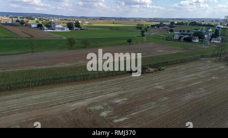 Vista aerea di agricoltori Amish raccolto i loro raccolti in una giornata autunnale con squadre di cavalli come visto da un drone Foto Stock