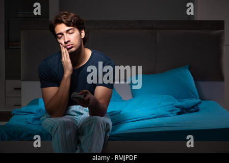 L'uomo guarda la TV di notte a letto Foto Stock