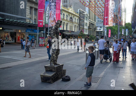 Melbourne, Australia - 1 Dicembre 2018: Boy guardando statua vivente, performer uomo di bronzo al tempo di Natale Foto Stock