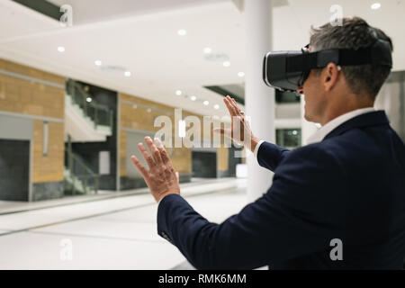 Imprenditore vivendo VR auricolare in corridoio Foto Stock