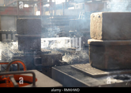 Il fumo deriva da stampi caldi di ghisa alla fine di versare in una fonderia Foto Stock