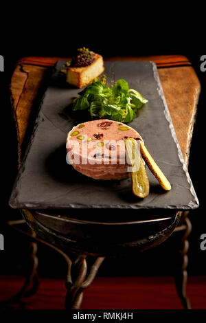 Delizioso paté d'anatra servito con una fetta di pane tostato e un sottaceti a fette Foto Stock