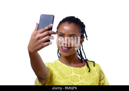 Allegro con la pelle scura donna prendendo selfie con lo smartphone contro uno sfondo bianco Foto Stock