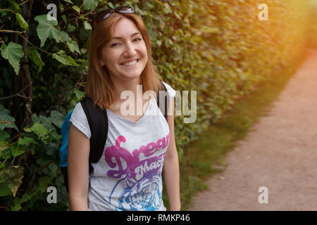 Close up ritratto di una giovane donna con uno zaino, la luce del sole. Foto Stock