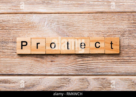 Proteggere la parola scritta sul blocco di legno. Proteggere il testo sul tavolo in legno per il desing, concetto. Foto Stock