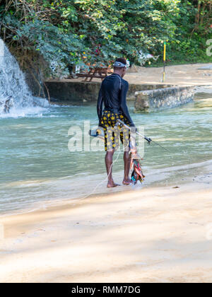 Ocho Rios Giamaica -4 Febbraio 2019: uomo sulla spiaggia con lancia pesca di cattura Foto Stock