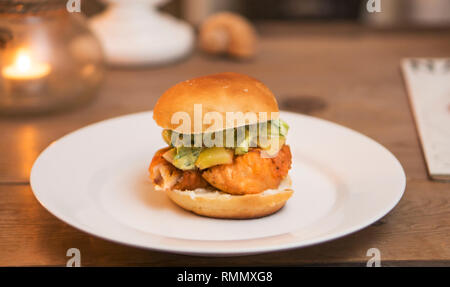 Sandwich di pesce fritto di cod burger con sottaceti dolci, salsa tartara, fresche bun, a lume di candela. Foto Stock