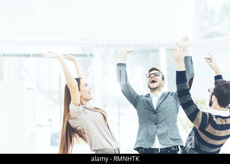 Concetto di vittoria - il giubilante team business in piedi in cerchio e con le mani fino a gioire il successo. Foto Stock