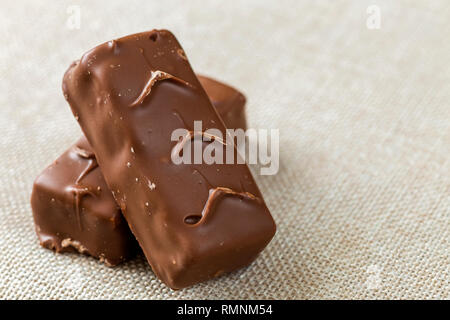 Due isolati isolato di color marrone scuro caramella di cioccolato snickers bar sulla luce tela panno spazio copia dello sfondo. Il cibo gustoso e nutriente merenda, concetto. Foto Stock