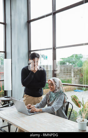 Guida esecutiva spiegando intern o nuovo dipendente con il hijab in ufficio Foto Stock