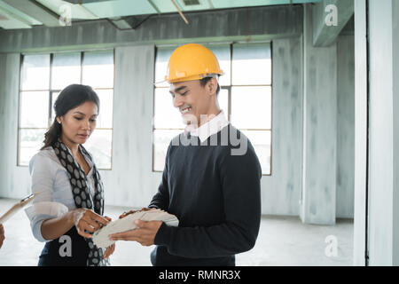 Imprenditore con hardhats protettivo di lavorare insieme e di discutere i dettagli del progetto sul sito Foto Stock