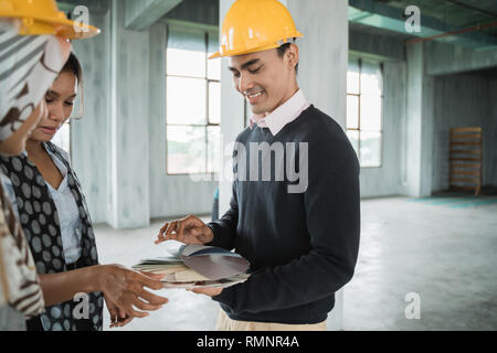 Imprenditore con hardhats protettivo di lavorare insieme e di discutere i dettagli del progetto sul sito Foto Stock