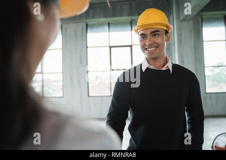 Imprenditore con hardhats protettivo di lavorare insieme e di discutere i dettagli del progetto sul sito Foto Stock