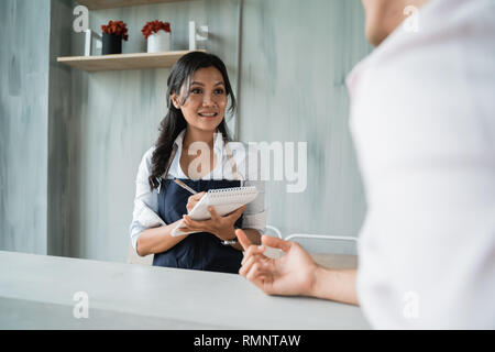 Femmina asiatica cameriera tenendo una nota su ordine del cliente in cafe Foto Stock