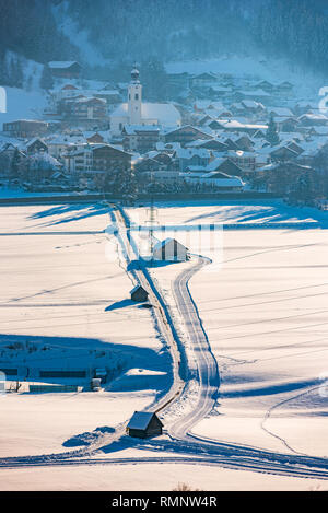 Svuotare strada in inverno al Haus, piccola città in Schladming-Dachstein, massiccio Dachstein, Liezen District, Stiria, Austria. Campanile di una chiesa sopra la città. Foto Stock