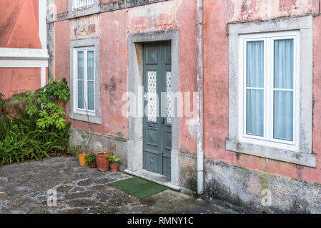 Porta ingresso della tradizionale casa di strada con cortile in ciottoli giardino nella città vecchia Cascais Portogallo Foto Stock