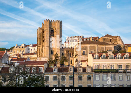 Vista sulla strada del quartiere di Alfama a Lisbona Portogallo con la Cattedrale Sé salendo al di sopra di vicini edifici di appartamenti Foto Stock
