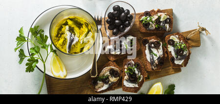 Banner di panini con Sarde marinate in olio di oliva con aglio e pane di segale. luce estiva antipasto italiano con limone e prezzemolo Foto Stock