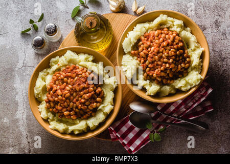 Purè di patate con stufato di fagioli bianchi in pomodori. riscaldamento invernale ricetta da cucina vegana Foto Stock