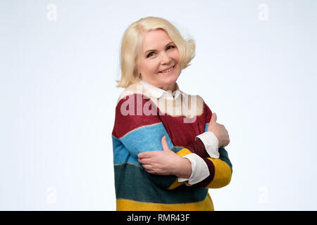 Fiducioso donna sorridente holding abbracciando se stessa. Ama te stesso concetto Foto Stock