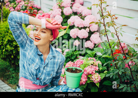 La cura dei fiori e irrigazione. suoli e fertilizzanti. hydrangea. La primavera e l'estate. donna felice giardiniere con fiori. donna cura dei fiori nel giardino Foto Stock