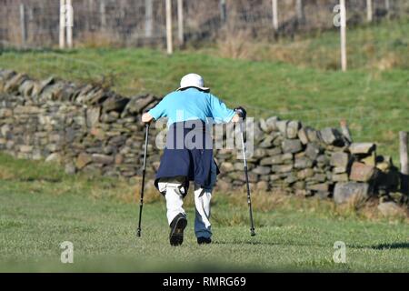 Un anziano uomo cammina su stampelle su una lunga passeggiata in alta area del picco del Derbyshire. Foto Stock