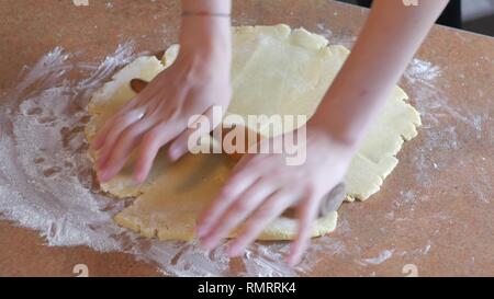 Baker gli impasti con il mattarello sul tavolo prepara il pane o la torta di mele Foto Stock