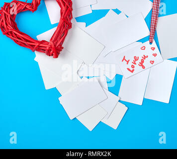 In vimini in legno cuore rosso e bianco vuoto di carta carte aziendali su sfondo blu Foto Stock