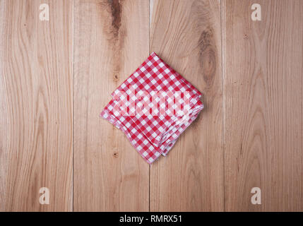 Rosso asciugamano tessile in una cella di bianco su uno sfondo di legno, spazio di copia Foto Stock