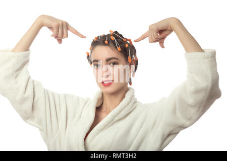 Giovane donna in accappatoio mostra in corrispondenza dei bigodini sulla testa, isolati su sfondo bianco Foto Stock