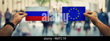 Due mani diverse bandiere, UE vs Federazione russa sulla politica arena oltre la strada affollata dello sfondo. La futura strategia, le relazioni tra il conte Foto Stock