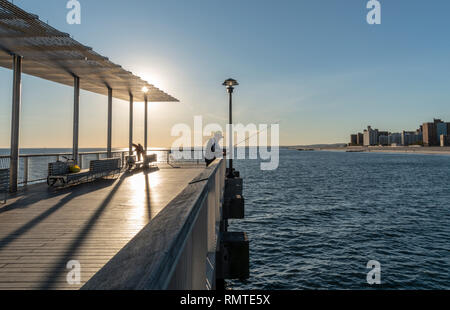 Pier a Coney Island la spiaggia di Brighton vicino al tramonto con il vecchio uomo di pesca. Foto Stock