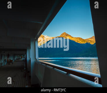 La mattina presto sunrise luce sulle montagne, dalla passeggiata esterna del ponte della nave da crociera, Taiya ingresso, Skagway, Alaska, Stati Uniti d'America. Foto Stock