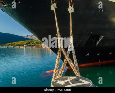 Linee di ormeggio con guardie di ratto che si estende dalla prua di una nave da crociera, legato a bollard al dock , Skagway Alaska, Stati Uniti d'America. Foto Stock