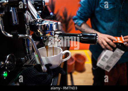 Fantasia di acciaio inossidabile macchina da caffè versando un doppio espresso in un coffee shop Foto Stock