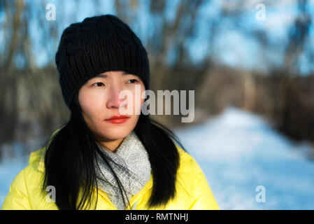 Un attraente donna cinese indossando un giallo giacca invernale guardando lontano dalla telecamera in una fredda giornata invernale in Sheffield Massachusetts nel tardo un Foto Stock