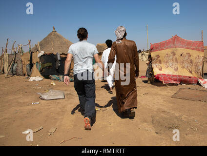 Rashaida man mano nella mano con un turista in un villaggio, Stato di Kassala, Kassala, Sudan Foto Stock