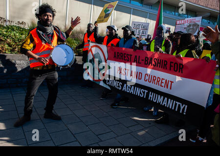Un batterista visto prima di manifestanti tenendo un banner e cartelloni durante la dimostrazione. Il comitato di coordinamento "udan Unite" nei Paesi Bassi per sostenere i sudanesi organizzato a marzo la Corte penale internazionale situato a L'Aia, in solidarietà con la rivoluzione in Sudan. Le persone si sono riunite a Malieveld e da lì la dimostrazione ha camminato per la Corte penale internazionale. Ci hanno chiesto l arresto di al-Bashir e tutti gli altri criminali, li costringono a stare in giudizio presso la Corte penale internazionale, aprire nuove indagini nella corrente di crimini contro l umanità e fermare la deportazione Foto Stock