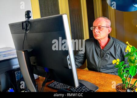 Uomo di mezza età con gli occhiali seduto alla scrivania. Uomo maturo che utilizzano personal computer. Concetto senior. Uomo che lavora in ufficio Foto Stock