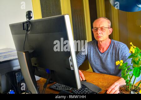 Imprenditore seduto in un ufficio presso il . Uomo di mezza età con gli occhiali seduto alla scrivania. Uomo maturo utilizzando il telefono cellulare. Concetto senior Foto Stock