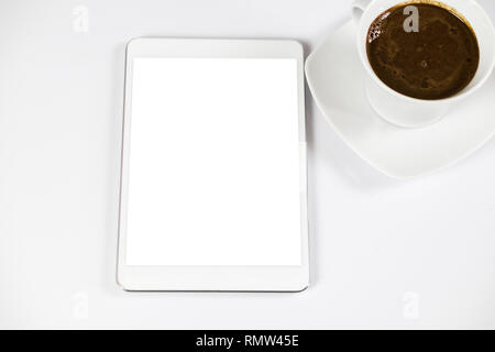 Computer tablet con bianco schermata vuota accanto al caffè. Il tablet è sul tavolo bianco. Vista dall'alto. Close-up. Foto Stock