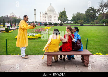 AGRA, Uttar Pradesh, India - Febbraio 24, 2015: famiglia indiana prendendo foto di gruppo con stranieri in abito rosso sul banco di lavoro nel giardino di fronte Taj Foto Stock