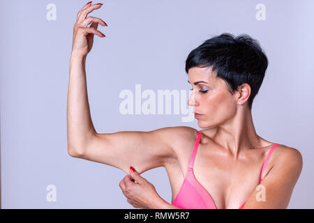 Calma giovane femmina adulta pizzicature e tendere la cute su tricipiti porzione di braccio piegato Foto Stock