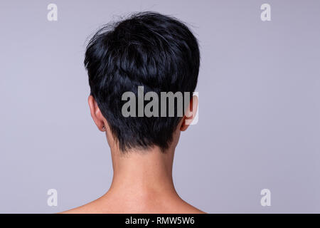 Vista posteriore di una testa di donna in breve capelli scuri su sfondo neutro Foto Stock