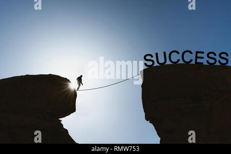 La silhouette di un uomo a piedi di bilanciamento sulla corda per il successo Foto Stock