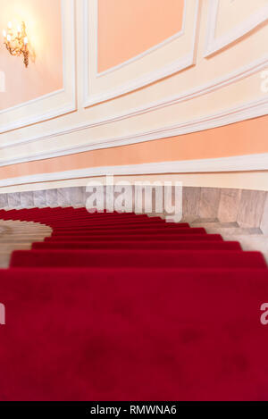 Tappeto rosso sulle scale a spirale fatta di marmo. Edificio lussuoso interno Foto Stock