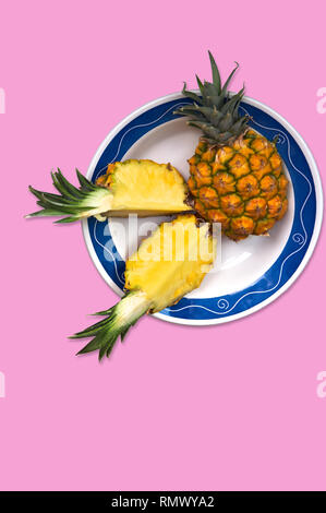 Ananas tagliato in segmenti per il consumo su una lastra decorata con toni di blu e uno sfondo rosa su cui aggiungere testi, spazio di copia Foto Stock