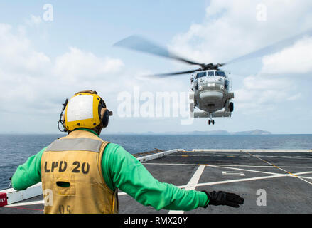 Stati Uniti Aviazione Navale meccanico strutturale di terza classe Andrew Jerauld, dal North Attleboro, Massachusetts, segnali un S-70B Seahawk elicottero, assegnato alla Marina Militare tailandese piattaforma di atterraggio dock nave HTMS Angthong (LPD 791), come si atterra sul ponte di volo del trasporto anfibio dock nave USS Green Bay (LPD 20) durante la croce deck operazioni di volo nel Golfo di Thailandia 14 Febbraio, 2019. Il Green Bay, parte della Vespa Anfibia Gruppo pronto, con avviato 31 Marine Expeditionary Unit (MEU), è in Thailandia per partecipare in esercizio Cobra Gold 2019. Cobra Gold è un esercizio di multinazionale co-sponsorizzato Foto Stock