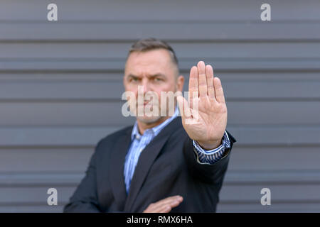 Grave uomo maturo che mostra il gesto di arresto con la mano, la messa a fuoco a portata di mano Foto Stock