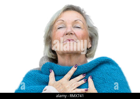 Attraente donna senior assaporando il momento in piedi con gli occhi chiusi e la testa inclinata indietro con un espressione serena come essa abbraccia il suo torace con h Foto Stock